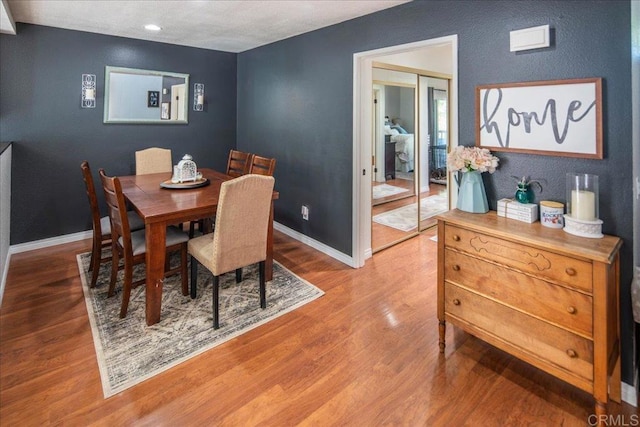 dining space with baseboards and wood finished floors