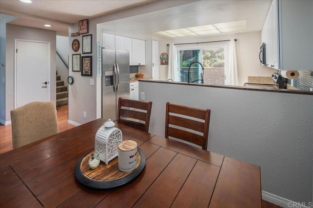 dining room featuring light wood finished floors, stairs, and baseboards