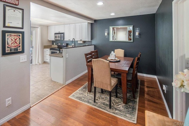 dining area with recessed lighting, light wood-style flooring, and baseboards