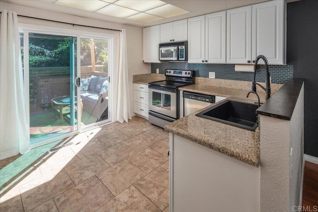 kitchen featuring tasteful backsplash, visible vents, appliances with stainless steel finishes, light stone countertops, and white cabinetry