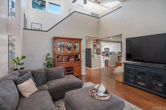 living room featuring wood finished floors, a ceiling fan, and baseboards