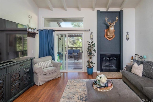 living room with beam ceiling, a fireplace, and wood finished floors