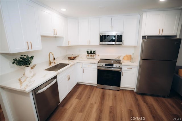 kitchen featuring light stone counters, stainless steel appliances, a sink, white cabinetry, and dark wood finished floors