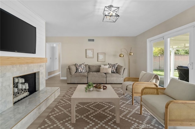 living room with visible vents, a fireplace with raised hearth, and wood finished floors