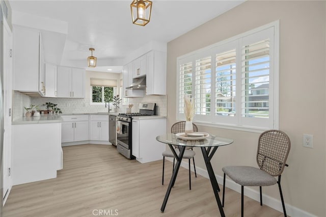 kitchen with tasteful backsplash, stainless steel gas range oven, white cabinetry, and under cabinet range hood