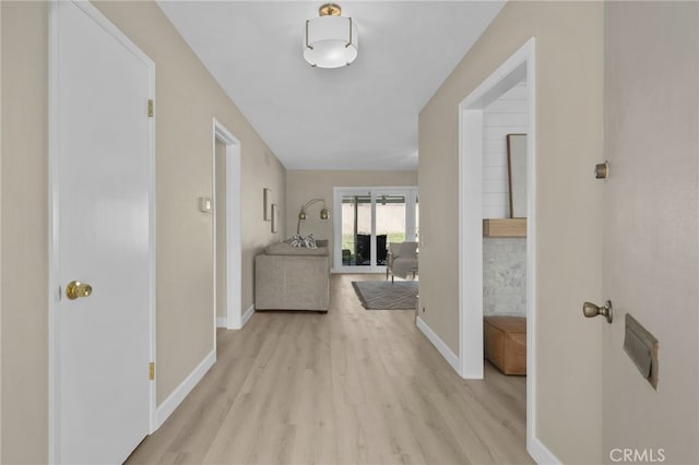 corridor featuring light wood-type flooring and baseboards