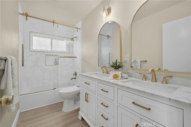 full bath featuring double vanity, combined bath / shower with glass door, a sink, and toilet