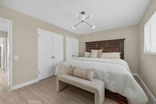 bedroom with light wood-type flooring, two closets, and baseboards