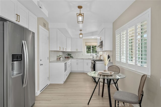 kitchen featuring appliances with stainless steel finishes, visible vents, decorative backsplash, and white cabinetry