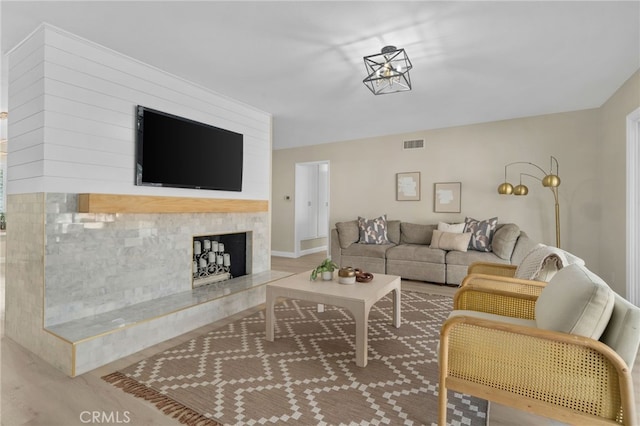 living room with a high end fireplace, visible vents, and wood finished floors