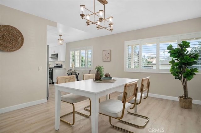 dining space featuring light wood finished floors, baseboards, and an inviting chandelier