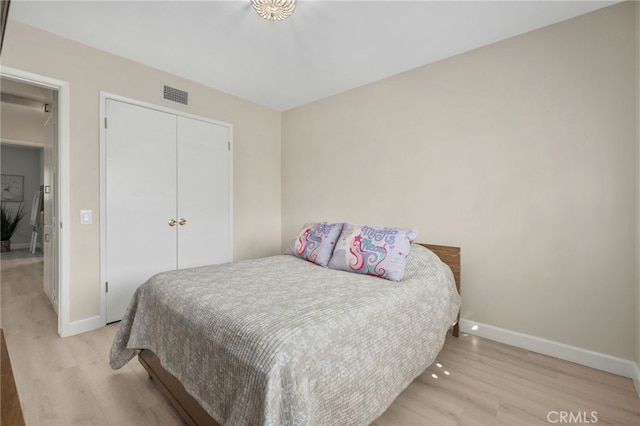 bedroom with light wood finished floors, a closet, visible vents, and baseboards