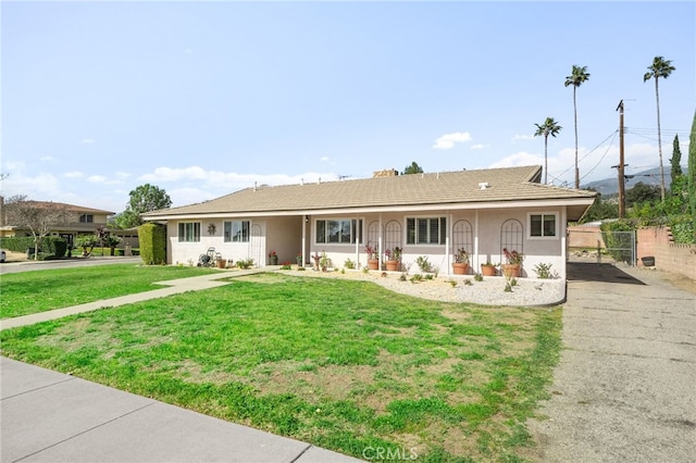 ranch-style home with a front yard, fence, and stucco siding