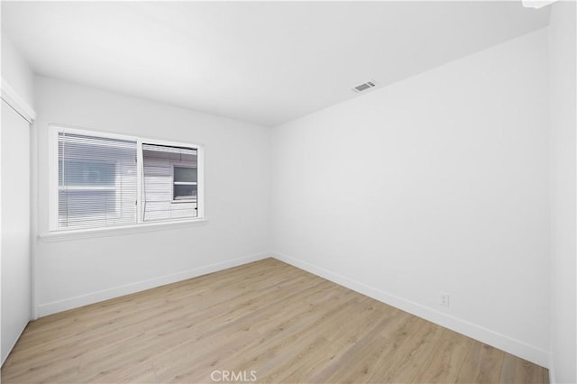 spare room with light wood-style flooring, visible vents, and baseboards