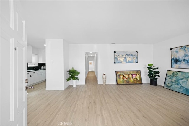 unfurnished living room with a sink and light wood-style flooring