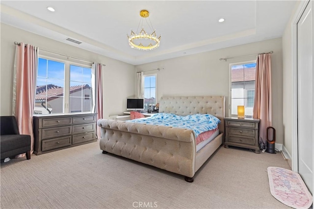 bedroom featuring a raised ceiling, visible vents, and multiple windows