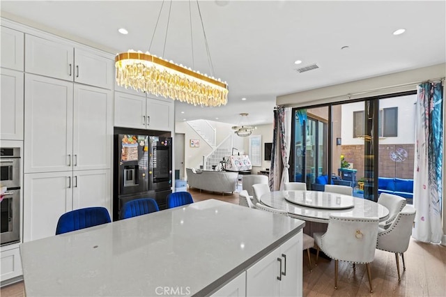 kitchen featuring hanging light fixtures, refrigerator with ice dispenser, and white cabinets