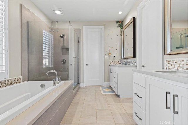 full bath with a sink, a garden tub, a healthy amount of sunlight, a shower stall, and two vanities