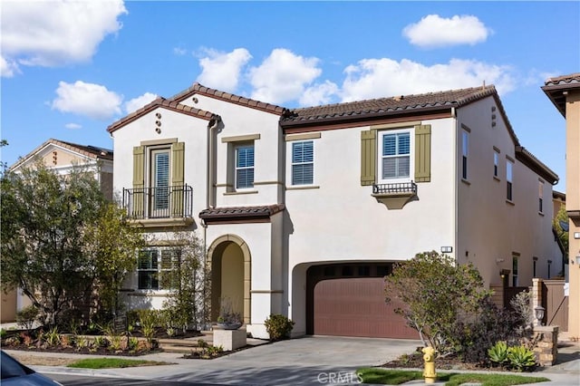 mediterranean / spanish-style home featuring a tile roof, driveway, an attached garage, and stucco siding