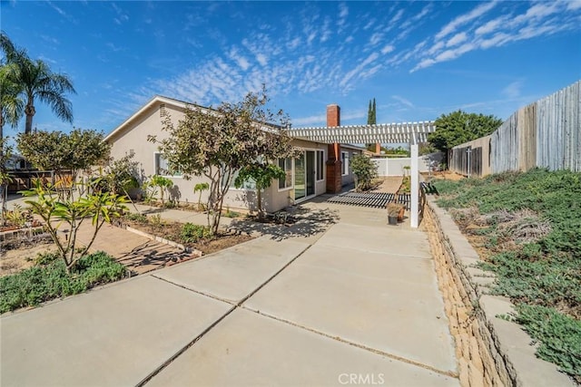 obstructed view of property featuring a patio area, a fenced backyard, a pergola, and stucco siding