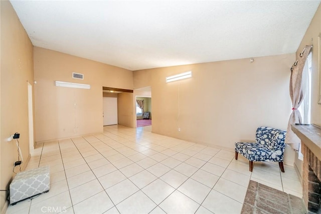 empty room with a healthy amount of sunlight, visible vents, vaulted ceiling, and light tile patterned flooring