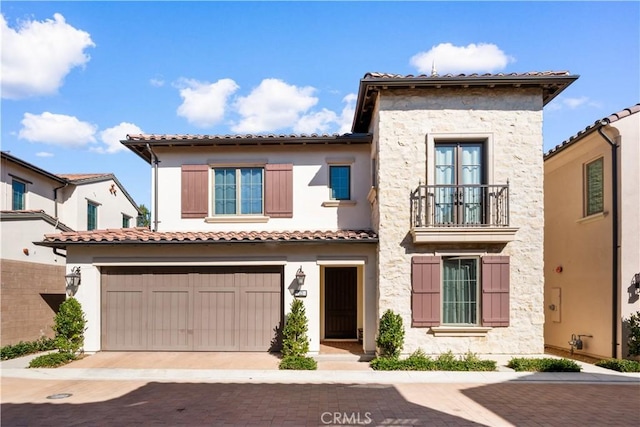 mediterranean / spanish-style home featuring a garage, decorative driveway, a tile roof, and stucco siding