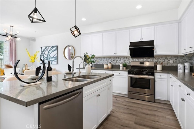 kitchen featuring appliances with stainless steel finishes, decorative backsplash, a sink, and wood finished floors