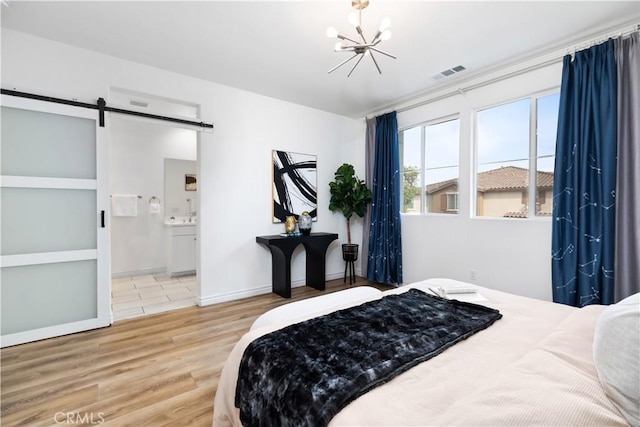 bedroom featuring a barn door, baseboards, visible vents, wood finished floors, and a chandelier