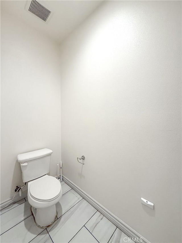 bathroom featuring baseboards, visible vents, and toilet