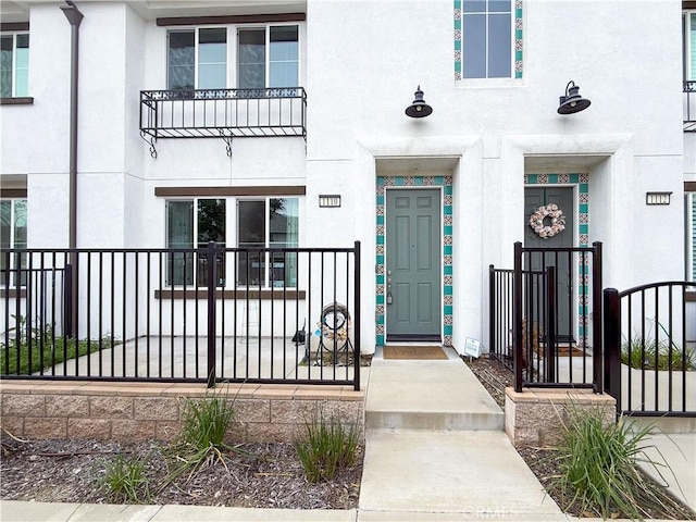 view of exterior entry with fence and stucco siding