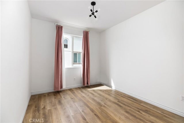 spare room featuring light wood finished floors and baseboards