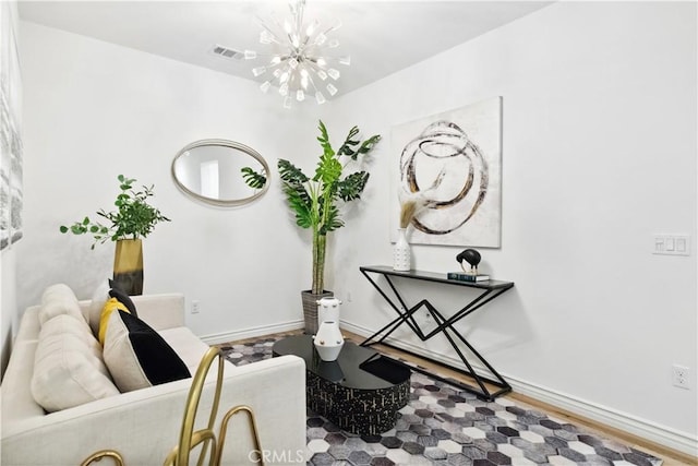 living area with visible vents, a notable chandelier, baseboards, and wood finished floors