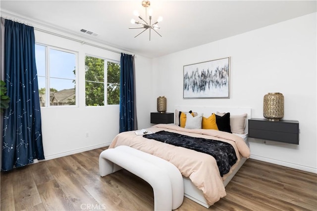 bedroom featuring baseboards, visible vents, a notable chandelier, and wood finished floors