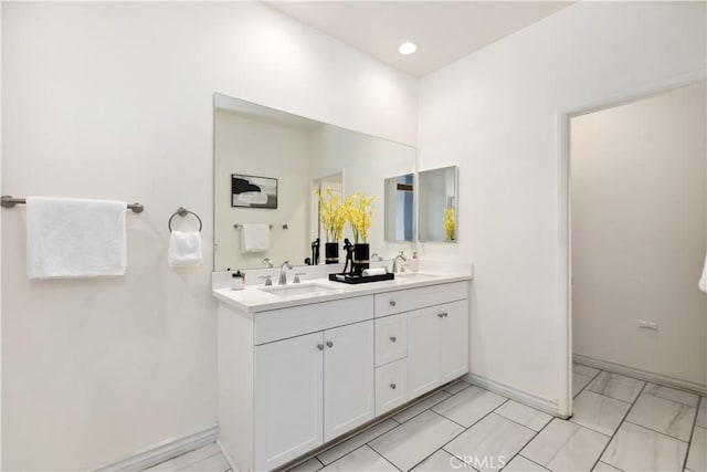 full bath featuring double vanity, recessed lighting, a sink, and baseboards