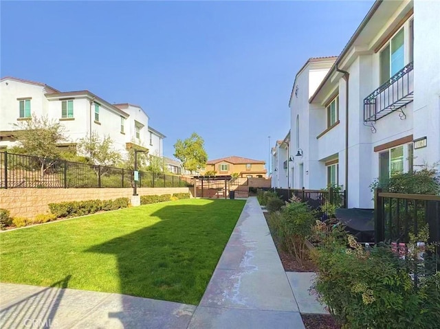 view of home's community featuring a residential view, fence, and a yard