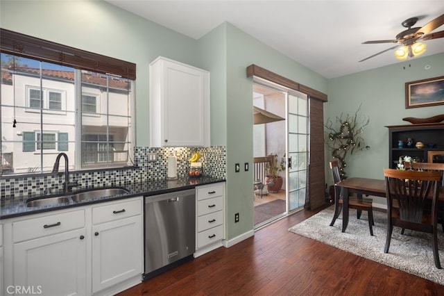 kitchen with a wealth of natural light, tasteful backsplash, dishwasher, dark wood-type flooring, and a sink