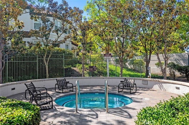 view of swimming pool with fence, a community hot tub, and a patio