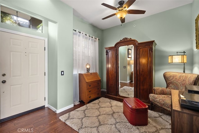 living area featuring ceiling fan, baseboards, and wood finished floors