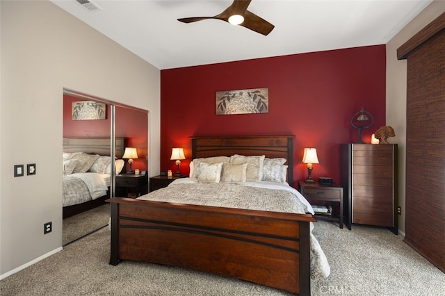 carpeted bedroom featuring an accent wall, a ceiling fan, visible vents, and baseboards