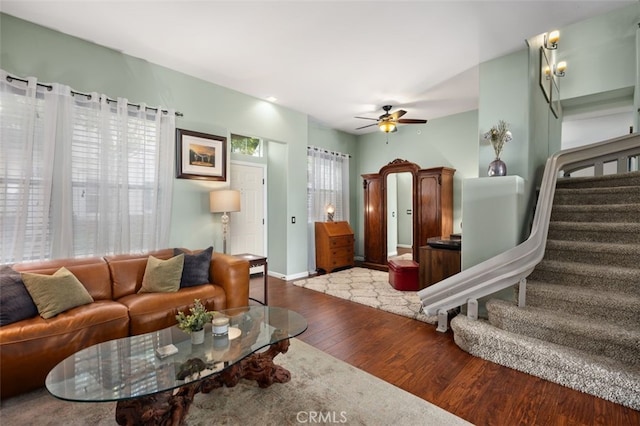 living room featuring baseboards, wood-type flooring, stairway, and a ceiling fan