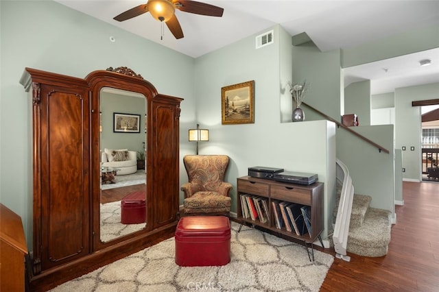 living area with ceiling fan, visible vents, stairway, and wood finished floors