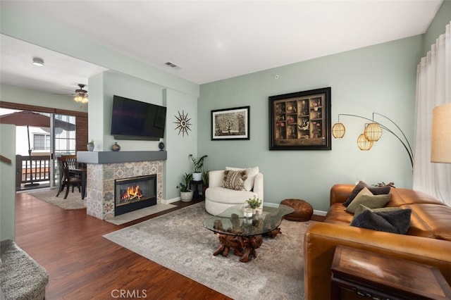 living area with baseboards, visible vents, a ceiling fan, wood finished floors, and a fireplace