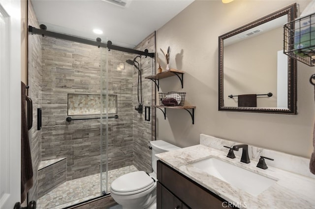 bathroom with visible vents, vanity, a shower stall, and toilet