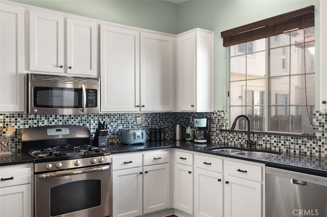 kitchen featuring white cabinetry, appliances with stainless steel finishes, decorative backsplash, and a sink