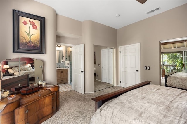 bedroom featuring ensuite bath, a sink, carpet flooring, visible vents, and two closets