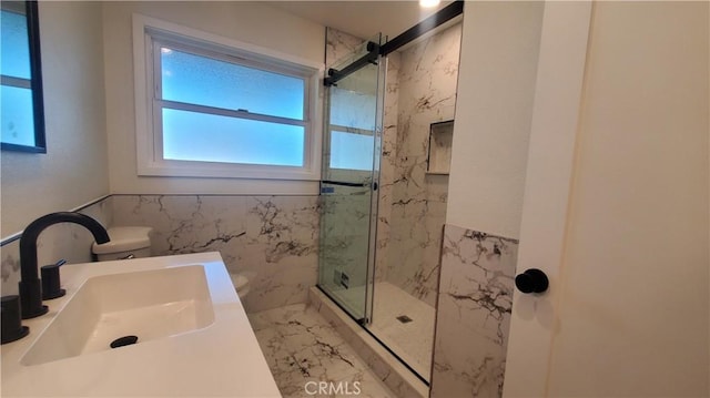 full bathroom featuring toilet, a sink, tile walls, marble finish floor, and a marble finish shower