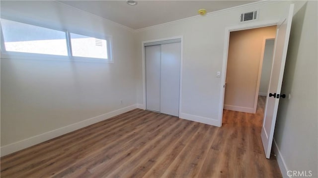 unfurnished bedroom with visible vents, crown molding, baseboards, and wood finished floors