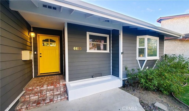 property entrance with covered porch and visible vents