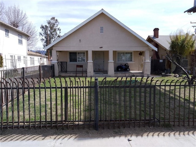 bungalow-style house featuring a porch, a fenced front yard, and stucco siding