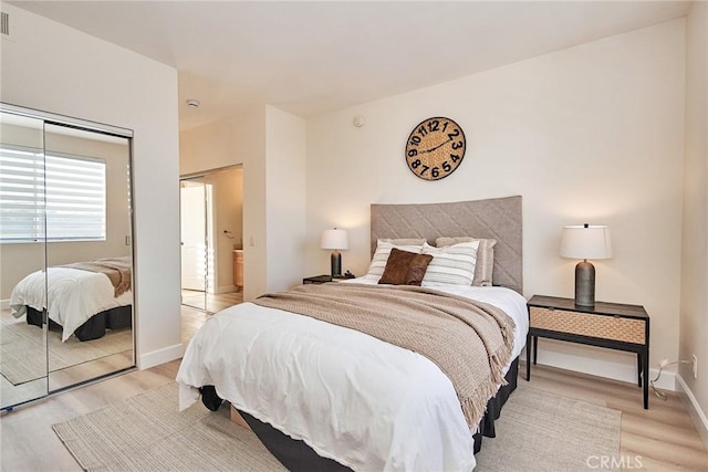 bedroom featuring light wood-style flooring, baseboards, and a closet